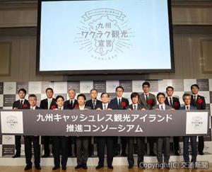 発表会で記念撮影する唐池座長（前列左から４人目）髙田副座長（同５人目）らコンソーシアム参画企業の関係者（九州キャッシュレス観光アイランド推進コンソーシアム提供）