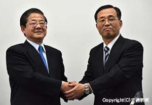 会見後に握手を交わす柘植社長（左）と金子次期社長