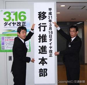 ダイヤ改正移行推進本部の看板を掛ける田畑本部長（右）と川戸部長
