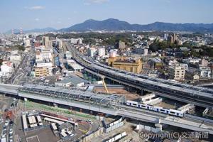 筑豊線（下）が高架化された折尾駅を北側上空から眺める。上は鹿児島線小倉方面。現在の同線は将来の短絡線ホームを一部使用。両線間では今後鹿児島線を移設する高架橋の工事が進む