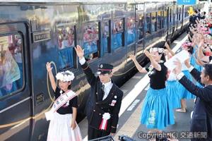 湯通堂駅長（右）と一日駅長の出発合図で発車する「指宿のたまて箱２号」＝指宿駅＝（ＪＲ九州提供）