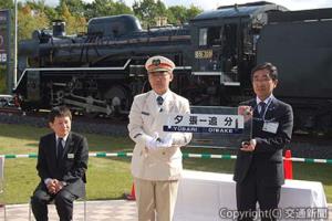一杉駅長からサボを受け取る及川町長（右）。左は戸川部長