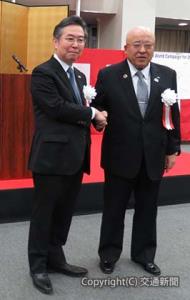 目標達成を祝い握手を交わす田端長官（左）と田川会長