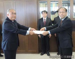 八木局長（左）から認可書を受け取る岡﨑社長