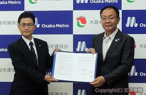 協定書を掲げる中村常務（左）と阪井会長