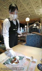 マスクやフェースシールド、手袋を着用して料理を運ぶ客室乗務員