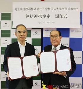 協定書を掲げる荻野社長（右）と久田学長（埼玉高速鉄道提供）