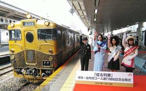 出発合図する鐘ケ江駅長（左端）とキャンペーンレディ