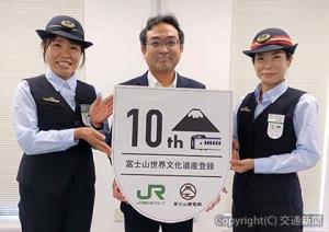 「10周年エンブレム」のデザインを掲げる内田英志執行役員・八王子支社長・八王子支社鉄道事業部長（中央）と大月駅社員