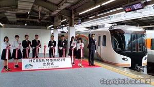 出発合図を行う伊藤駅長（右端）とテープカットする丹羽社長（左から５人目）ら