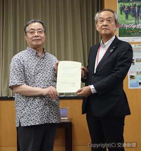 谷大臣（左）から通知書を受け取る藤田理事長（鉄道建設・運輸施設整備支援機構提供）