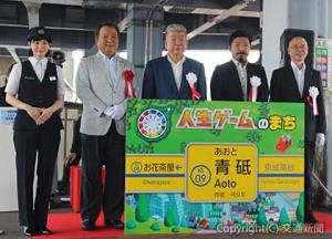 駅名看板除幕後に記念撮影する小林社長（中央）、富山副社長（右から２人目）、青木区長（右端）ら