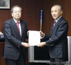 斉藤大臣（左）に報告書を手渡す中村座長