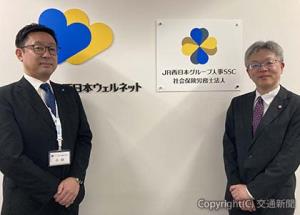 看板を除幕した小林社長（左）と大村社員＝ジェイアール西日本ウェルネット提供＝