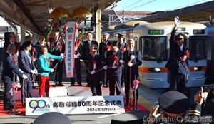 鶴田駅長（右）の出発合図に続いてくす玉を開花した近藤支社長（前列右端）ら