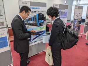 学生に応対する車両メーカーの担当者。Ｊ―ＲＡＩＬは日本機械学会（交通・物流部門）が主催、電気学会と土木学会が共催しました