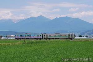 富良野線を行く普通列車。十勝岳連峰と田園風景が魅力の路線＝西中―ラベンダー畑間＝