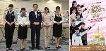 ㊧会見した古宮社長（中央）とＨＫＴ48のメンバー ㊨プロジェクトのポスター（福岡県）＝ポスターJR九州提供＝