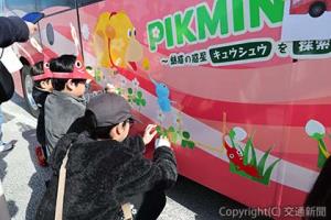 〝マイレール〟意識の醸成・向上を図ったピクミンラッピング企画で仕上げのシールを張る沿線の小学生（ＪＲ九州提供）