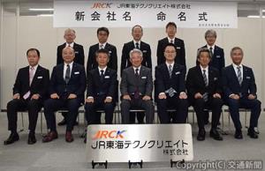 新社名の看板を前に記念撮影する上野社長（前列中央）ら