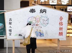 駅社員が描いた２種類の「ジャンボ絵馬」が掲げられ、訪れる人々が思い思いの願いを書き込む