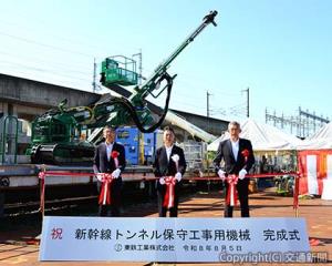 「上向きロックボルトマシン」「スライドバスケット」の前でテープカットする伊勢社長（中央）、長澤設備部長（左）、下山社長