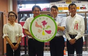 ヘッドマークのレプリカと記念撮影する三戸社長（右から２人目）、桂川会長（同３人目）ら