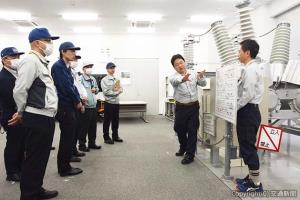 変電実習室で交流遮断器を見学する参加者